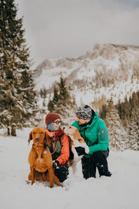 Dogs and couple on snow covered field