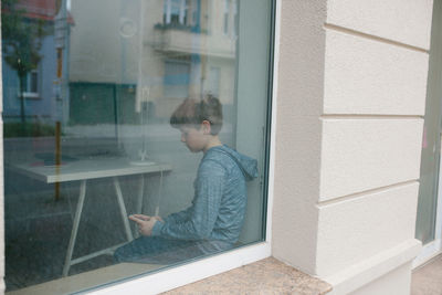 Side view of man looking through window in building