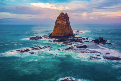 Rock formation on sea shore against sky