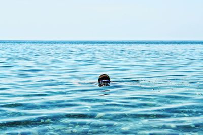 Man swimming in sea against clear sky