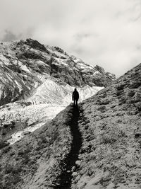 Rear view of person walking on mountain against sky