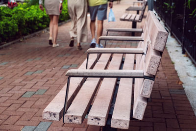 Benches and rear view of people walking on footpath
