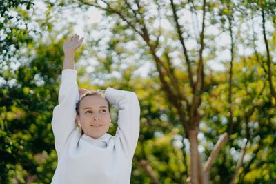 Young woman looking away while standing outdoors