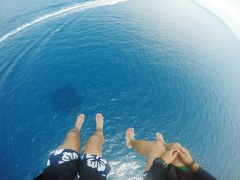 Low section of people paragliding over sea