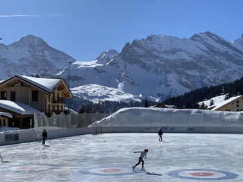 People skating on snowcapped mountain against sky in murren