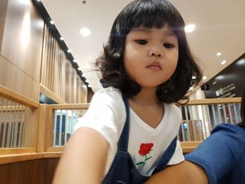 Portrait of girl sitting on book at home