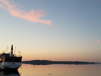 Sailboats moored on sea against sky during sunset