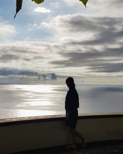 Side view of woman looking at sea against sky