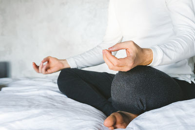 Low section of woman sitting on bed