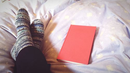 Low section of woman wearing socks relaxing on bed