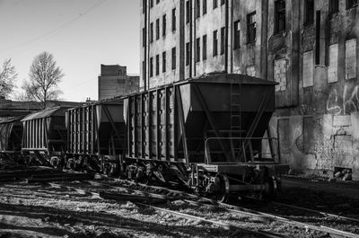 Abandoned railroad tracks by buildings against sky