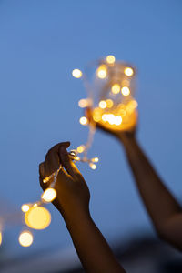 Midsection of woman holding illuminated light against sky at night