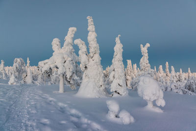 Snow covered land against clear blue sky