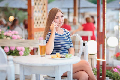 Portrait of woman drinking beer at beach cafe