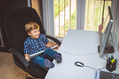 High angle view of cute boy using computer on desk at home