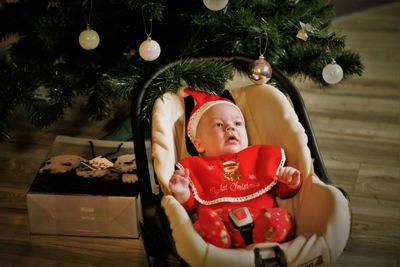 Portrait of happy girl sitting on christmas tree at home