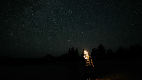 Trees on field against sky at night