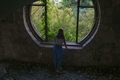 Rear view of woman standing by window