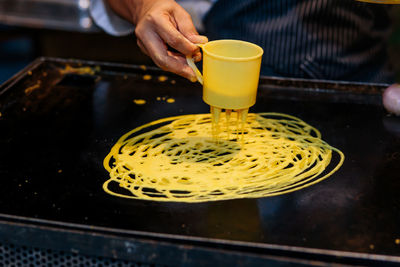 Midsection of person preparing drink in kitchen