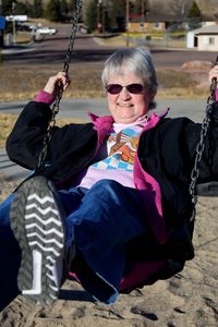 Portrait of woman with sunglasses swinging outdoors
