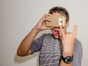 Boy watching virtual reality while gesturing against white background