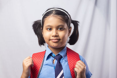 Portrait of a happy smiling indian girl child student in blue school uniform with red bag