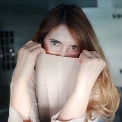 Close-up portrait of woman covering face sitting at home