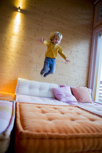 Little boy jumping on the couch at home