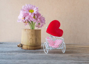 Close-up of pink flowers in vase on table against wall