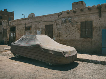 Abandoned car on street against buildings