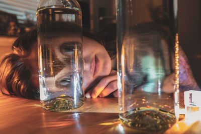 Portrait of woman looking through glass bottle