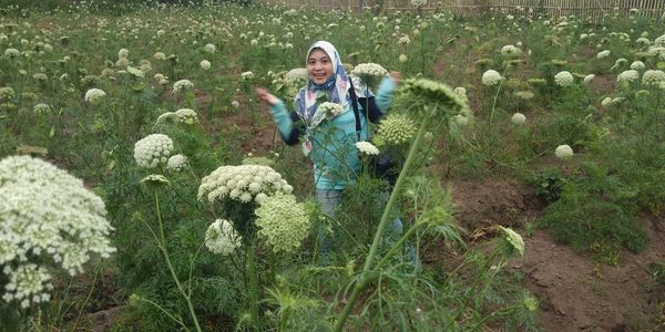 Portrait of smiling woman standing by plants