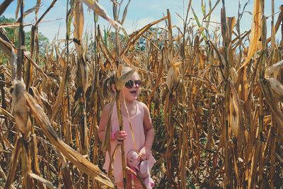 Young standing in corn field against sky