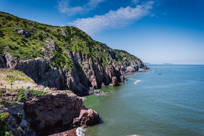 Scenic view of sea and mountains against blue sky