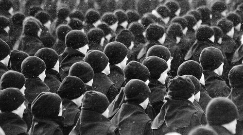 A group of military personnel stand in formation on a cold day. 