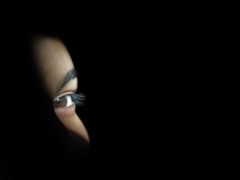 Close-up portrait of woman against black background