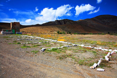 Landscape by mountain against cloudy sky