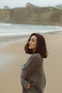 Side view of young woman standing at beach