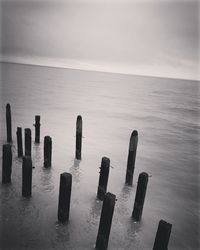 Close-up of wooden posts in sea against sky