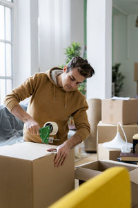 Full length of young man holding paper in box