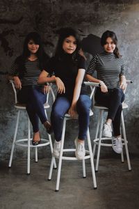 Portrait of a smiling young women sitting against wall