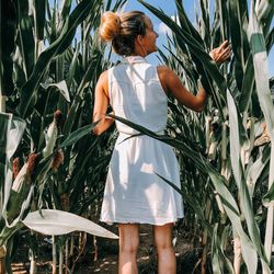 Rear view of woman standing amidst crops on field