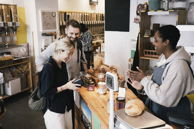 Happy cashier talking with customers at checkout counter in supermarket