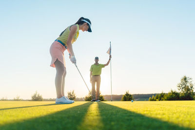 Low angle view of people playing golf against clear sky