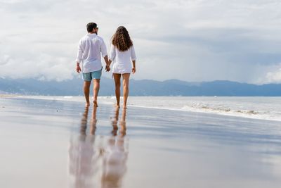 Rear view of couple walking on beach