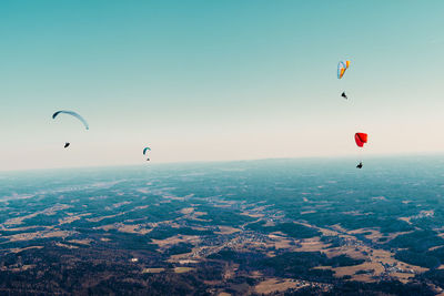 Aerial view of paragliding over landscape against sky