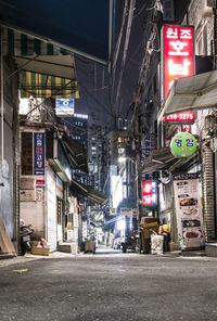 Illuminated street amidst buildings in city at night