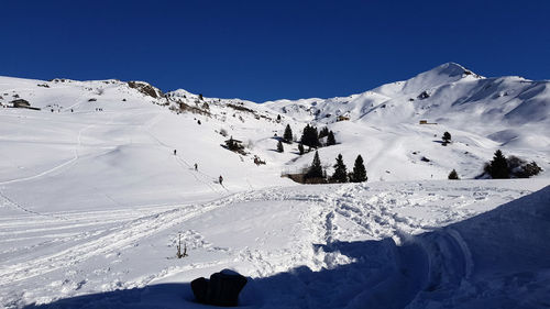 Scenic view of snow covered mountains against clear blue sky