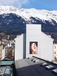 Woman standing by building against mountain in winter