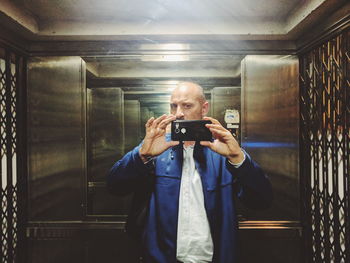 Man taking selfie of reflection in elevator